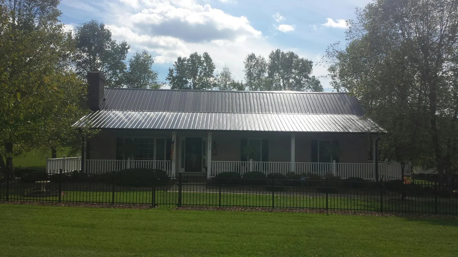 Gray metal roof on a brick ranch with a full width front porch — Gutter Guard Installation work by our crew in Conesville