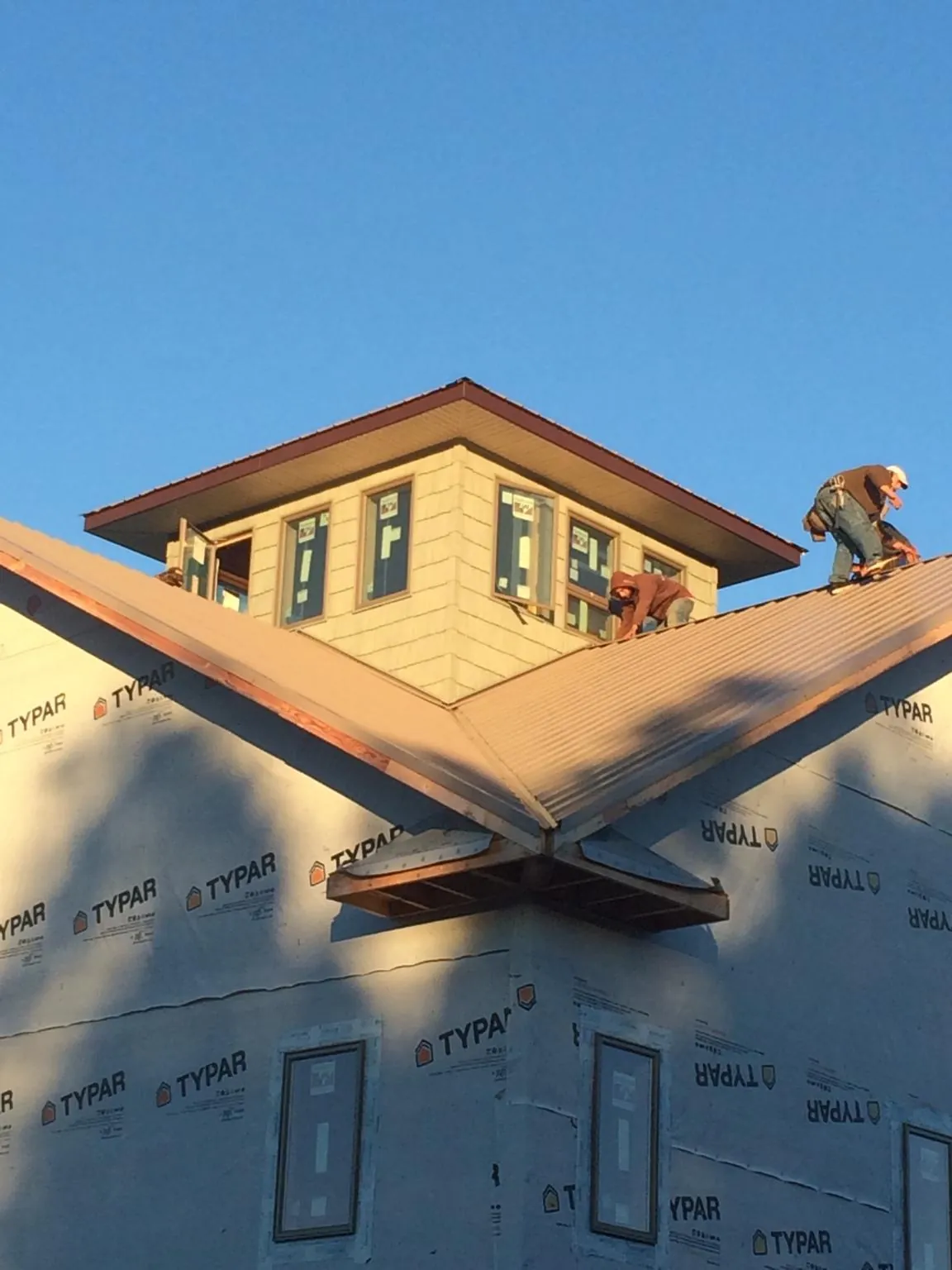 Roofers working around a rooftop cupola on a new metal roof at sunset — Roof Waterproofing in Conesville by Roofing Brothers